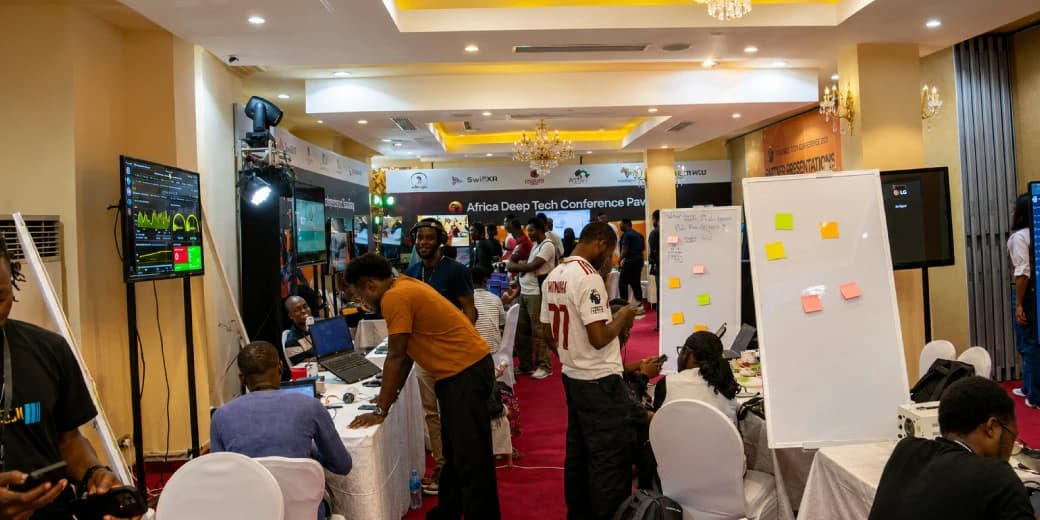 Developers and technology exhibitors demonstrating laptop projects at an African deep-tech event. Image credit: Techpoint.