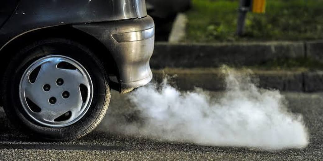 Car exhaust releasing smoke during a vehicle emissions discussion.