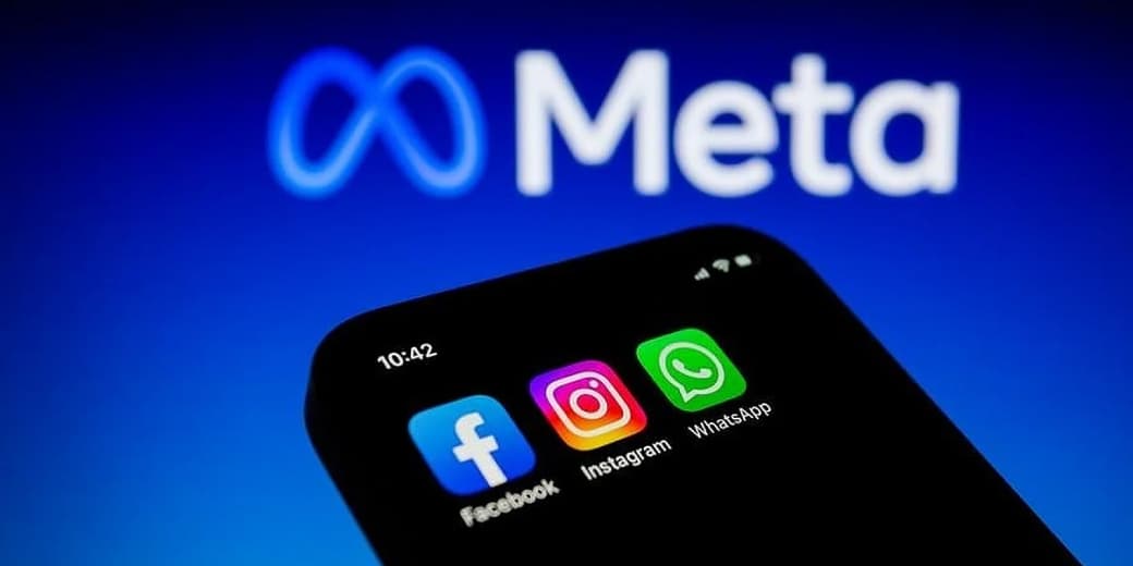 Meta logo behind Facebook, Instagram and WhatsApp app icons on a smartphone.