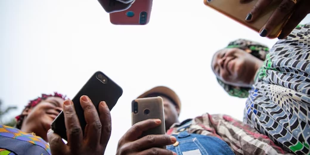 A group of people holding mobile phones while checking airtime and data. Credit: Webphatic.