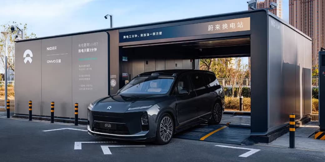 Dark grey Nio ES8 electric SUV positioned at the entrance of a Nio battery swapping station.