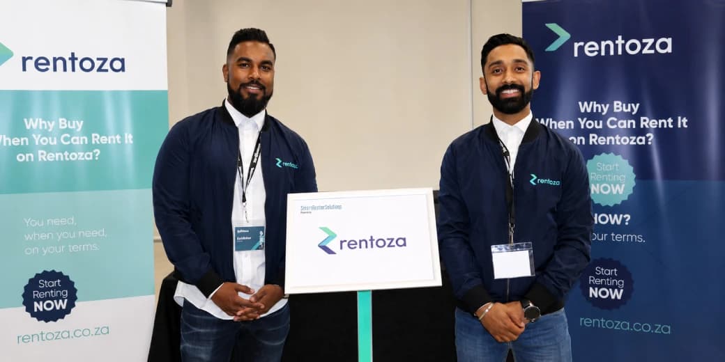 Two Rentoza representatives standing between branded company displays.