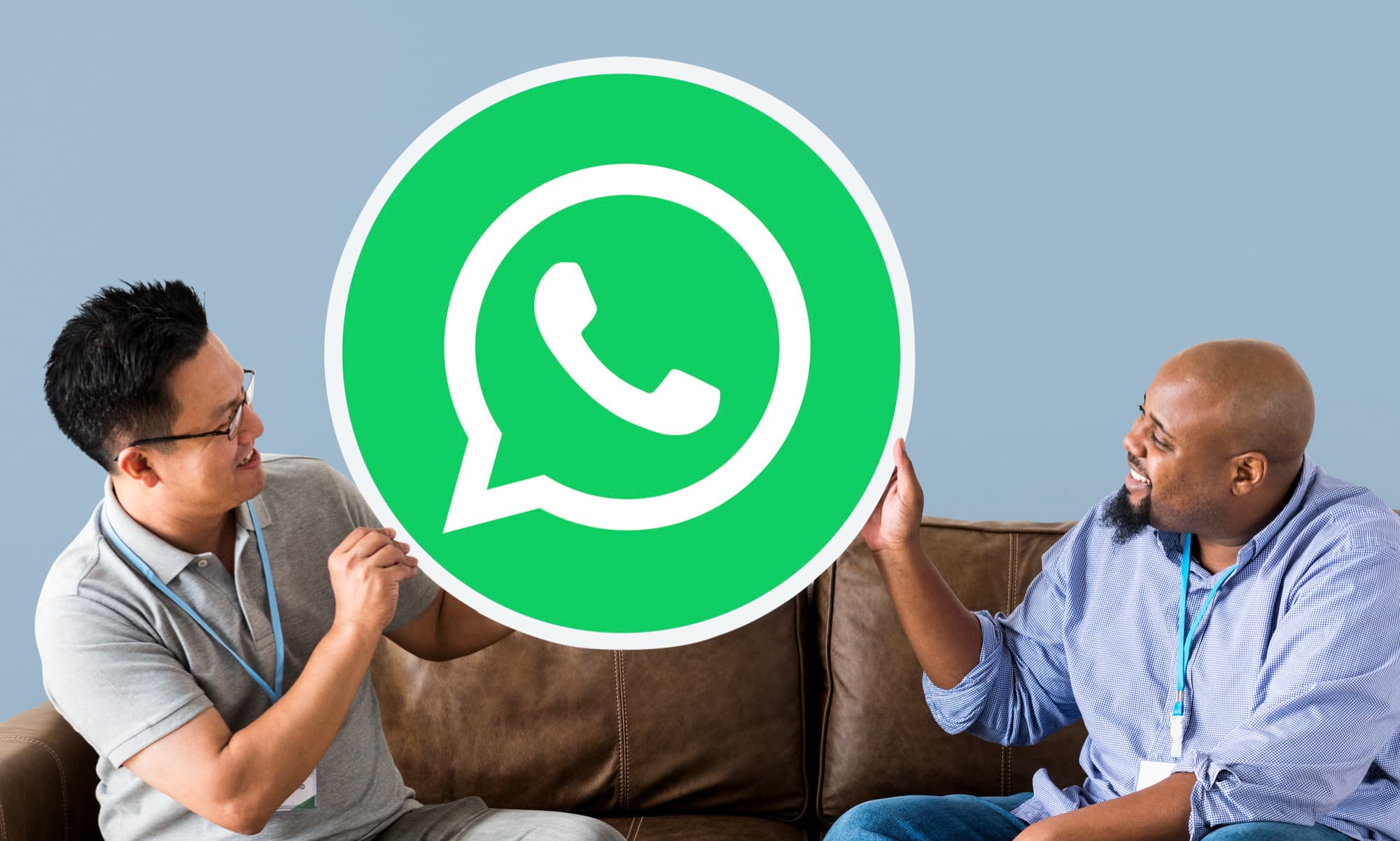 Two people holding a large WhatsApp logo.